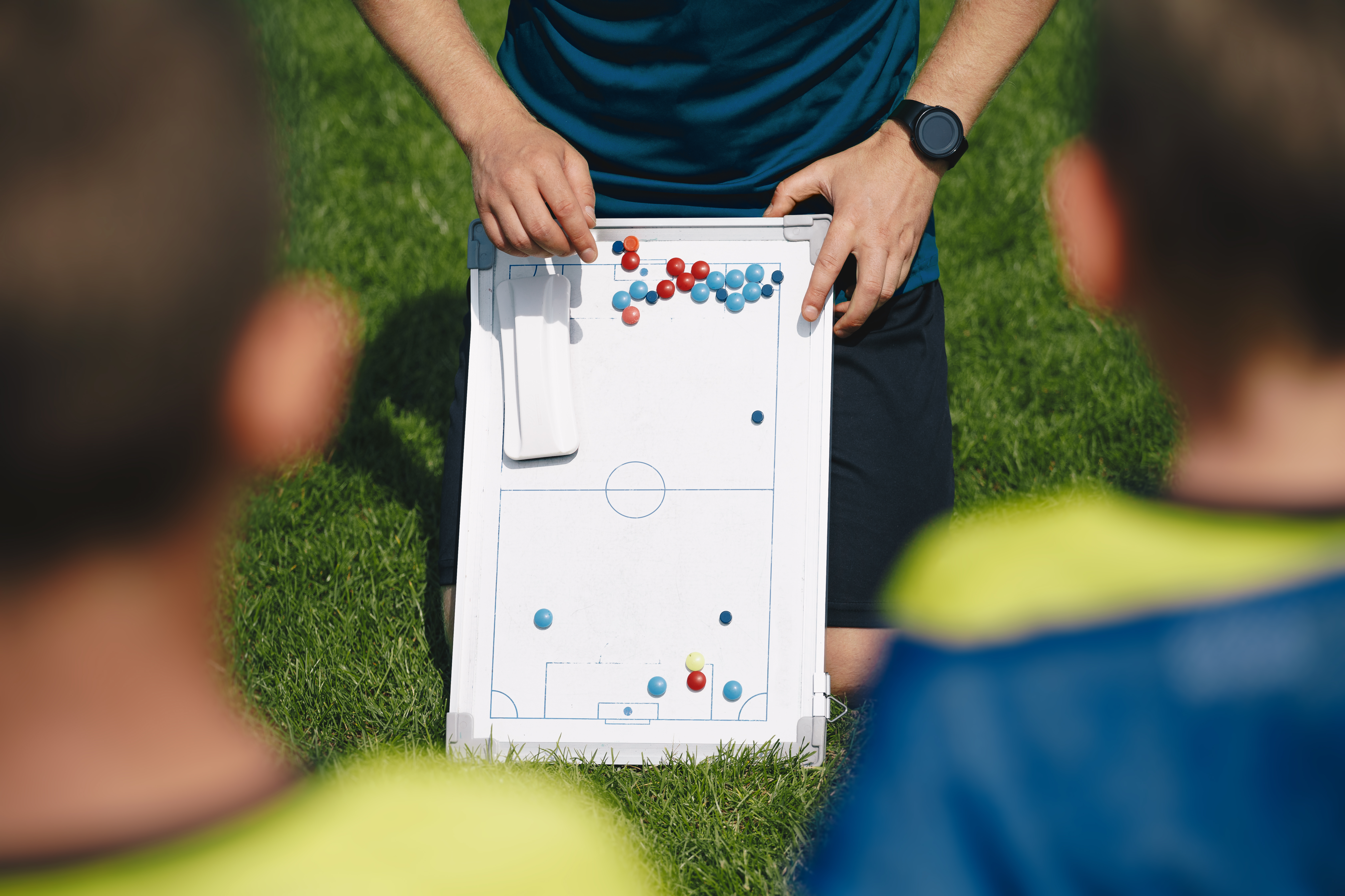 Sports junior team coach explaining soccer stratego for the game on training session. Education kids in sports
