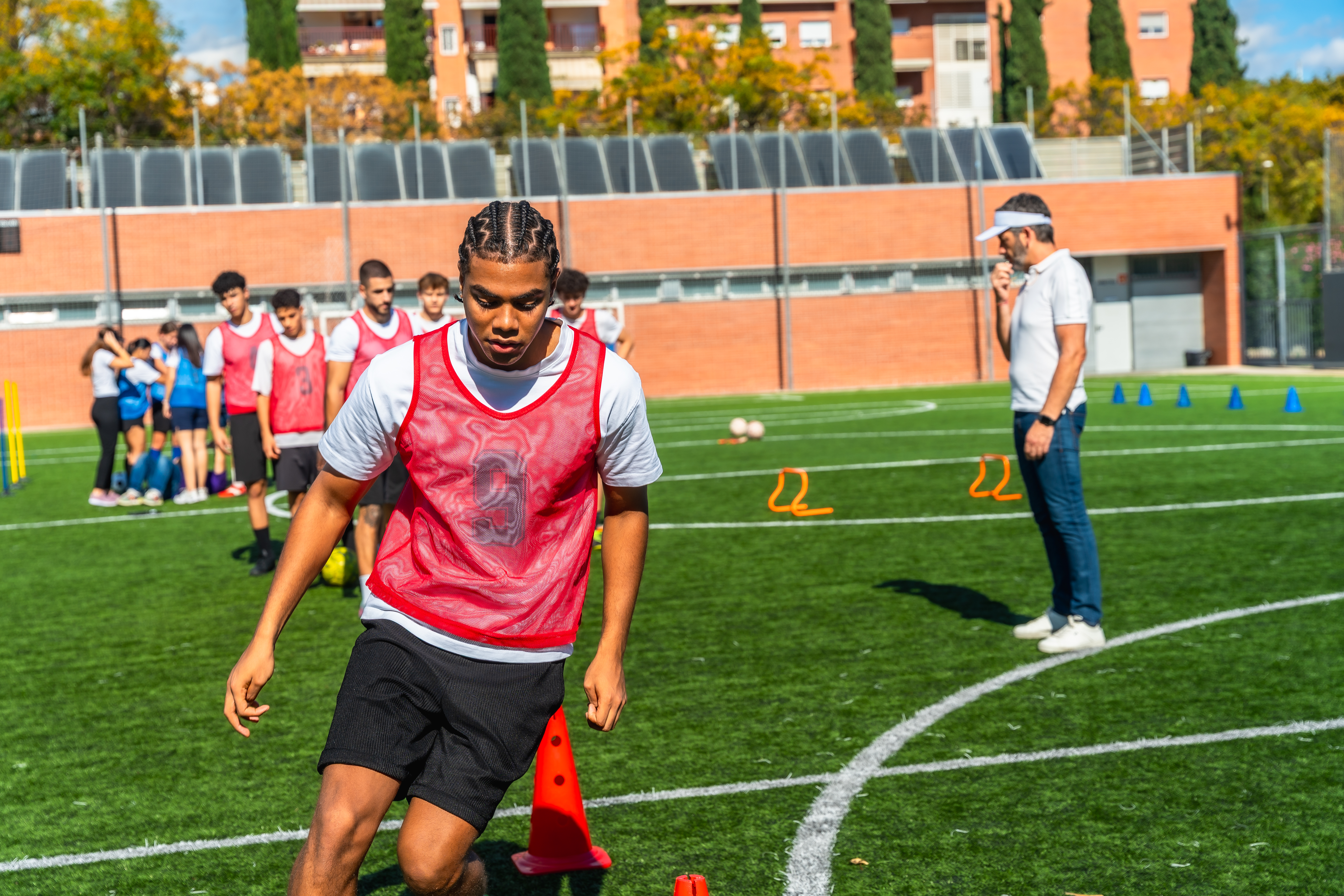 Young male athletes train on green artificial turf, practicing soccer drills under a coach's guidance to build teamwork, skill, fitness and focus during outdoor practice